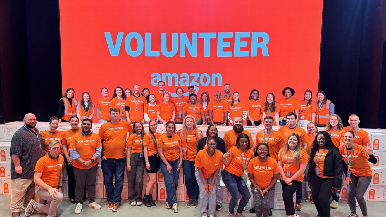 Large group of Amazon volunteers in orange shirts posing together