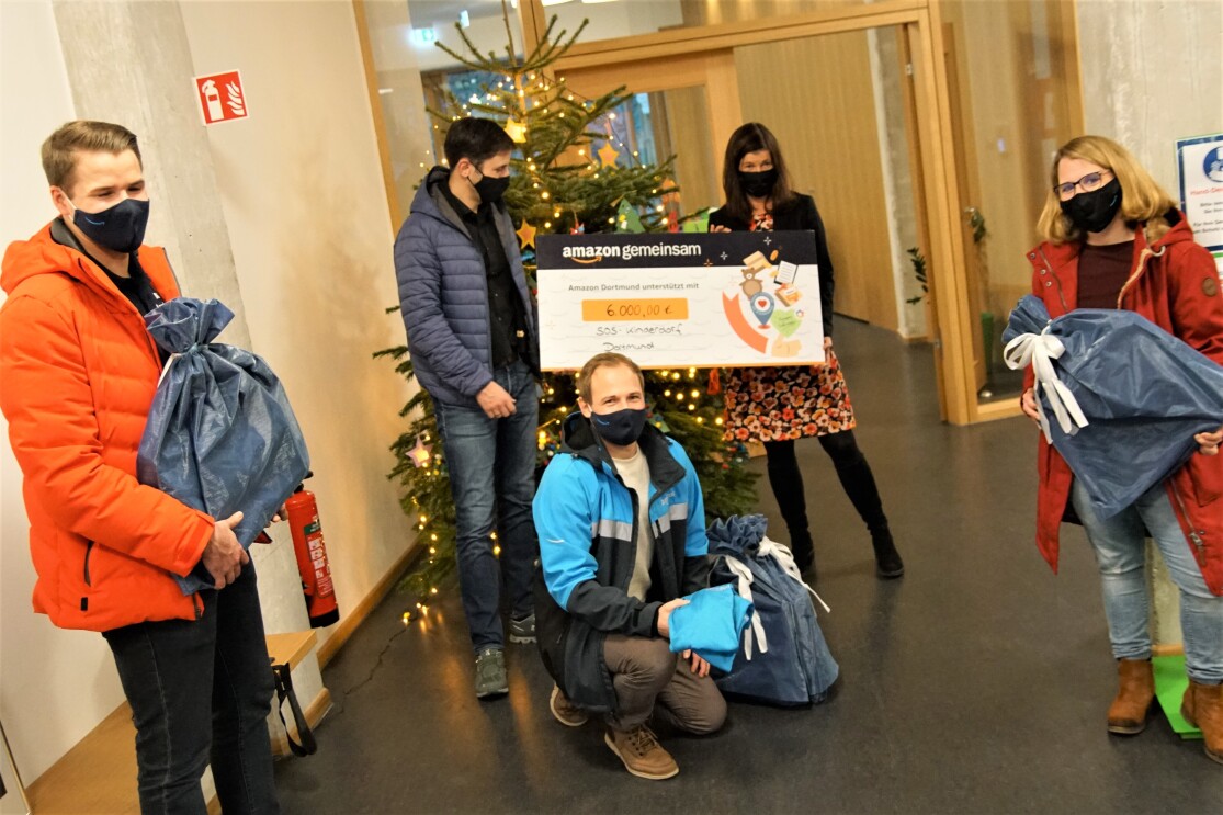 Verschiedene Personen vor einem Weihnachtsbaum mit spendenscheck