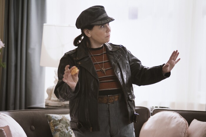 An image of Suzi from the marvelous mrs. maisel. She is wearing a hat and a black leather jacket with jeans and a striped shirt.