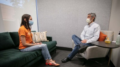 一男一女坐在诊所里，戴着口罩交谈。