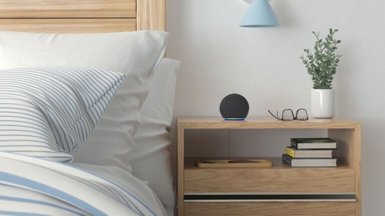 The Amazon Echo Dot sitting on a beside table.