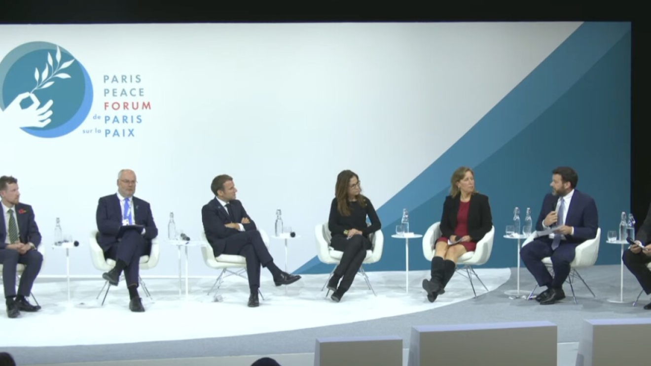 5 men and two women sit on a stage during a conference