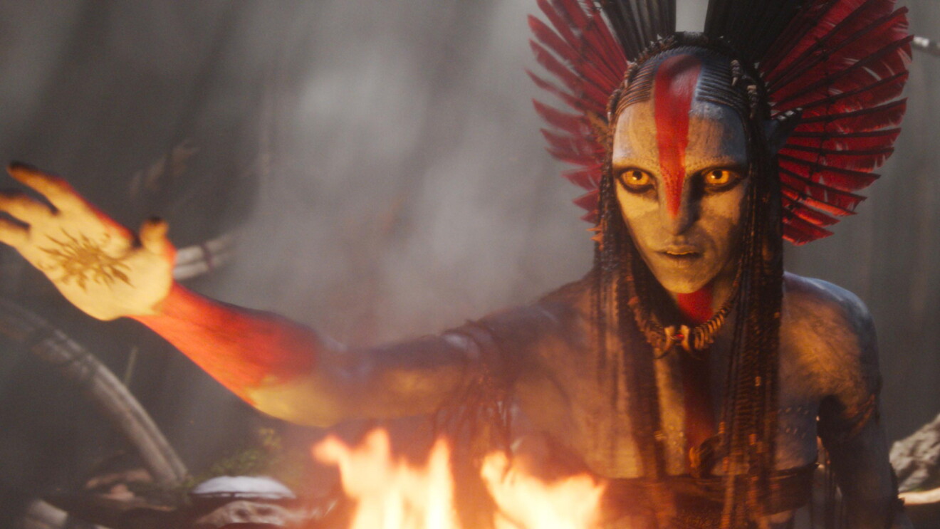 Fierce alien shaman with red headdress performing ritual by fire
