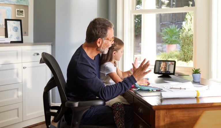 Father and daughter engaging in virtual call via Echo device by sunny window
