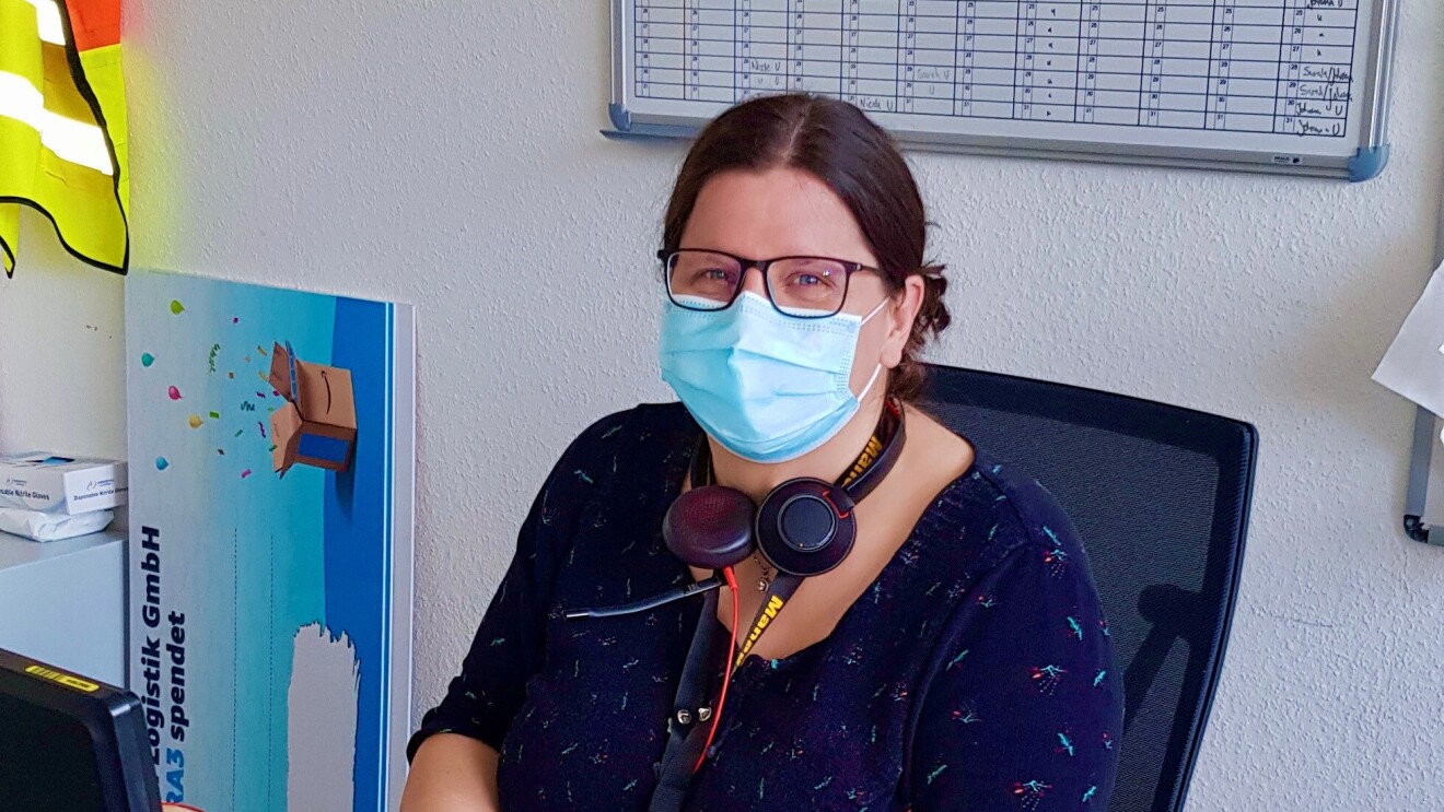 Silvana mit Maske am Schreibtisch.