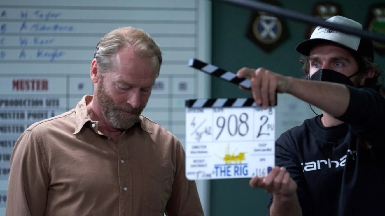 assistant director holds clapper board in front of actor during scene being filmed