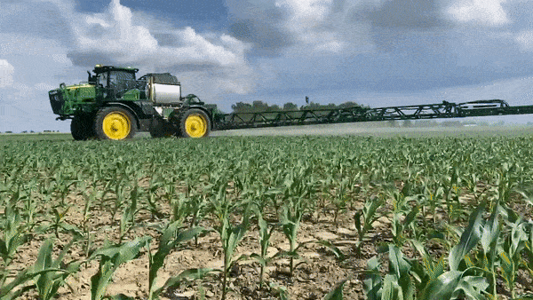 图为拖拉机在田里给庄稼喷洒农药