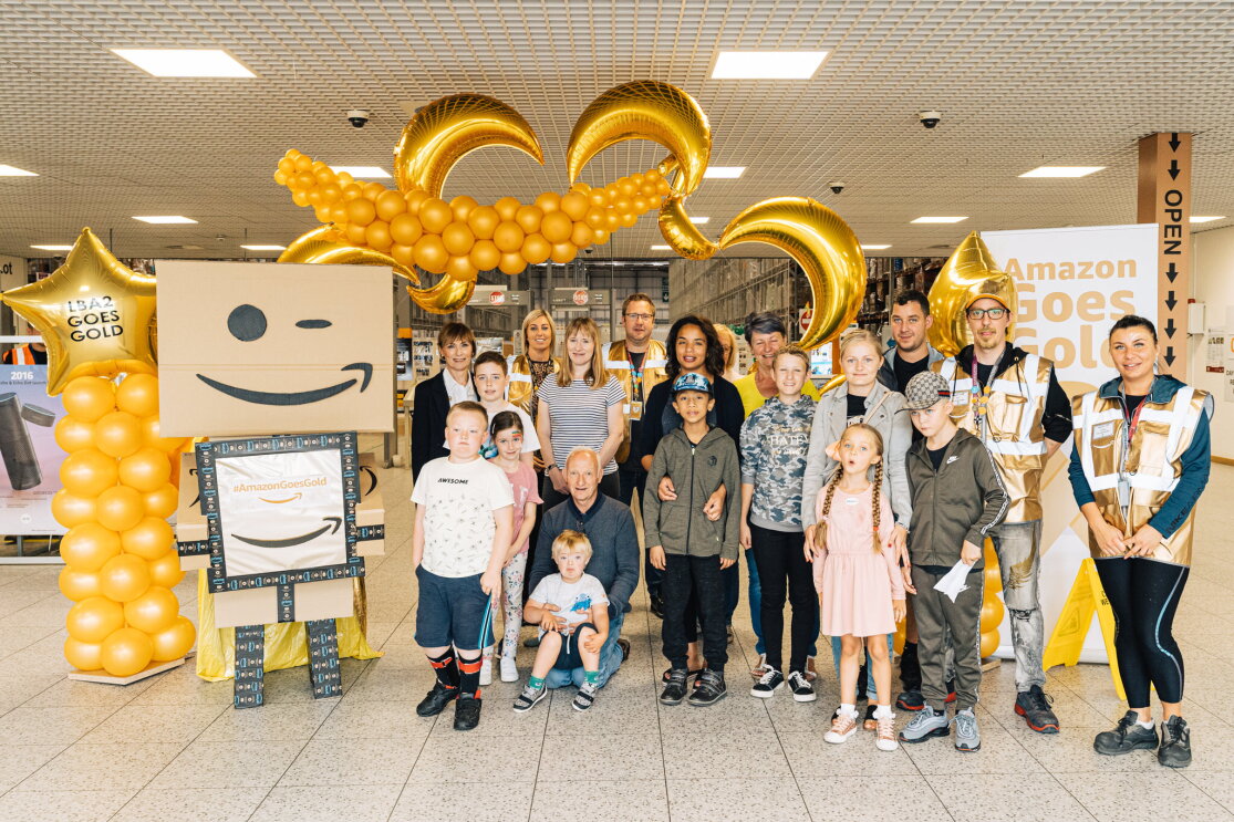 Amazon Goes Gold: golden decorations, children and Amazon employees with golden vests inside an Amazon fulfilment centre