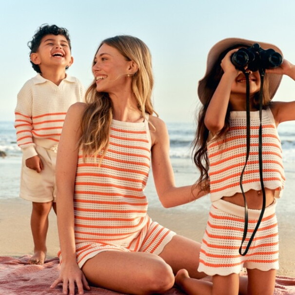 Eine Frau sitzt mit lachenden Kindern am Strand