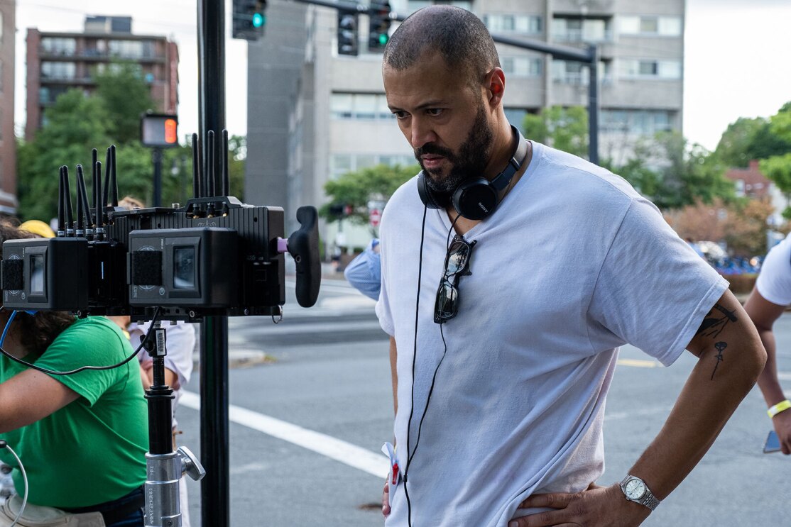 An image of Cord Jefferson standing on a city sidewalk looking into a camera on the set for American Fiction