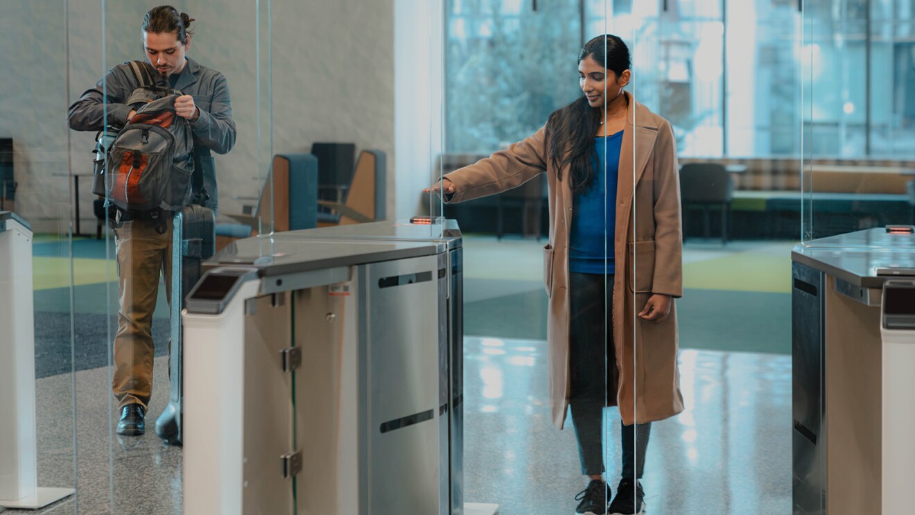 A photo of an employee walking into an office, and entering a security gate using Amazon One palm recognition technology.