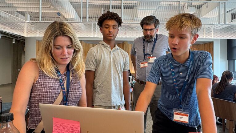Group collaborating on laptop in modern office space