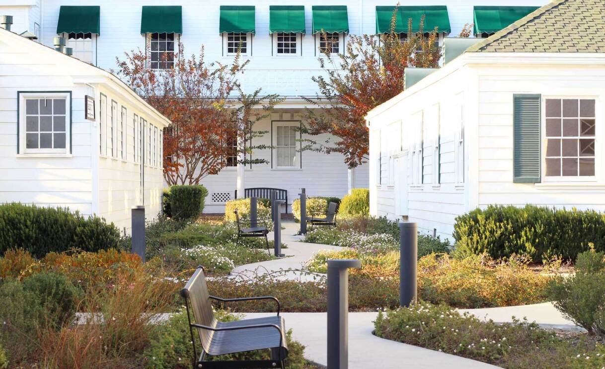 An image of several small, white buildings with green landscaping and winding sidewalks around them