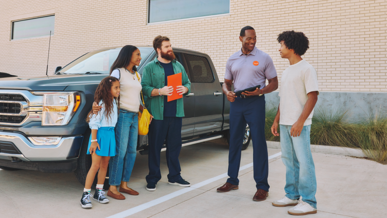 Family chatting to Amazon Autos representative after successfully purchasing a vehicle.
