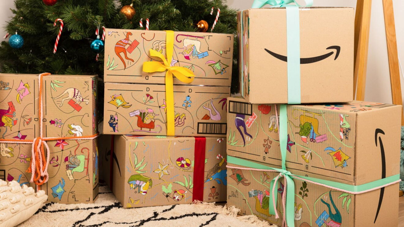 A pile of Amazon Christmas boxes next to a Christmas tree.