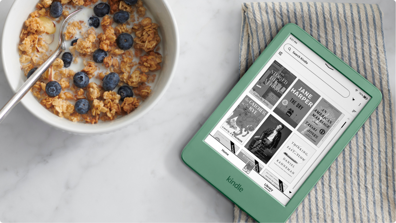 A green Kindle lying on a breakfast table next to a bowl of cereal