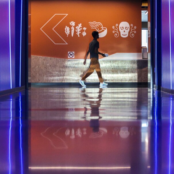 Amazon employee walks in the frame of the neon blue hallway at Day 1.