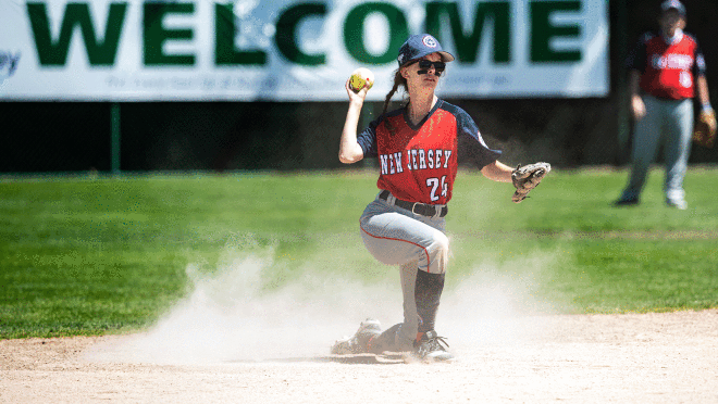 一个图像的垒球运动员单膝跪下。人扔一个球,戴着一顶帽子和手套。
