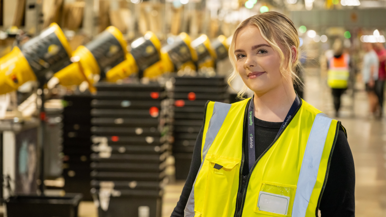 Female Amazon Employee posing in a high-vis jacket at the fulfilment center.