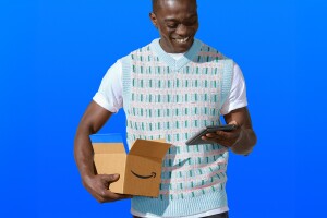 Smiling person holding Amazon package and device against blue background