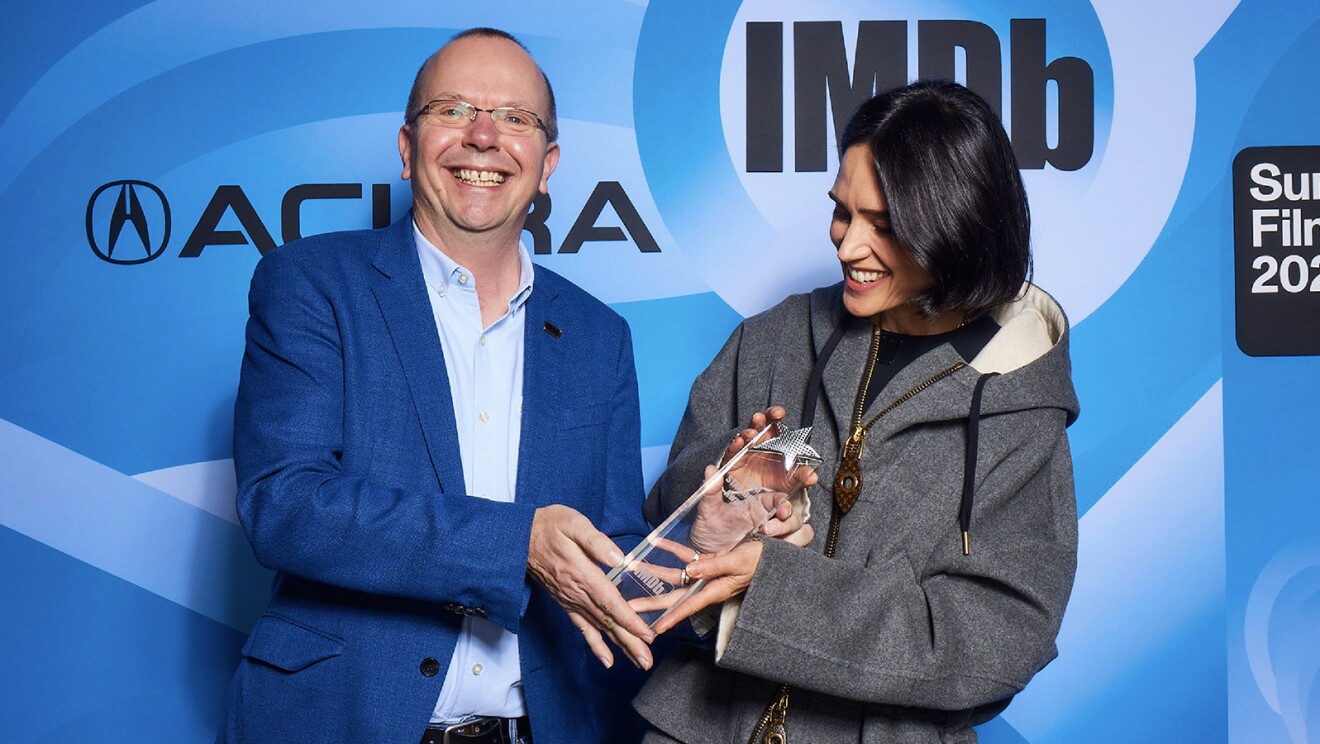 A photo of Col Needham, founder and CEO of IMDb, presenting an award to Jennifer Conelly.