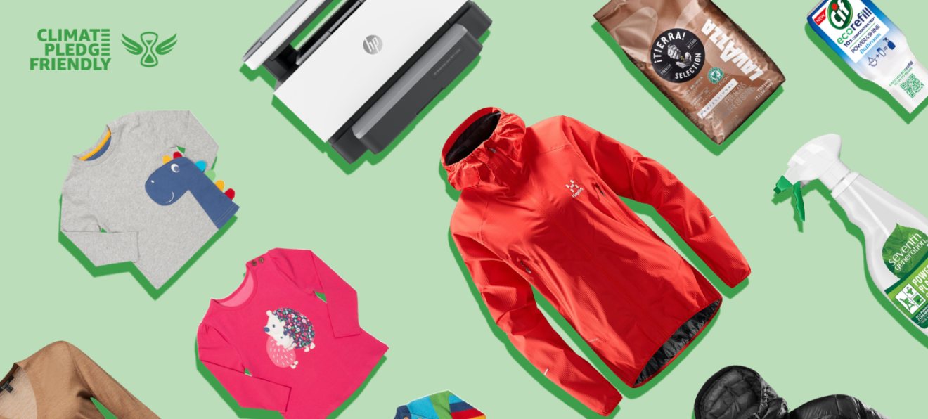 Con un fondo verde está el logo y la letras Climate Pledge Friendly en la esquina superior izquierda. Después hay productos superpuestos: un chubasquero rojo, un jersey marrón de cuello de pico, una camiseta rosa con un erizo y otra gris con un dinosaurio, una impresora, un paquete de café y dos productos de limpieza.
