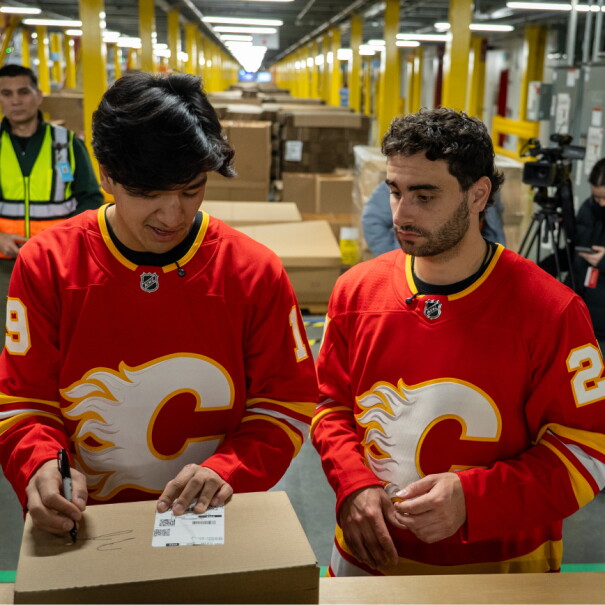 Two Calgary Flames hockey players packing Amazon boxes