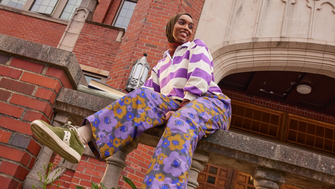 Prime Day 2023 live blog best deals: woman sitting on a ledge in front of a brick building.