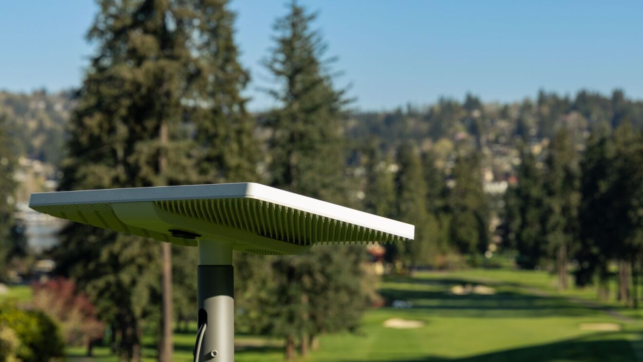 White rectangular panel on a post overlooking a tree-lined golf course fairway