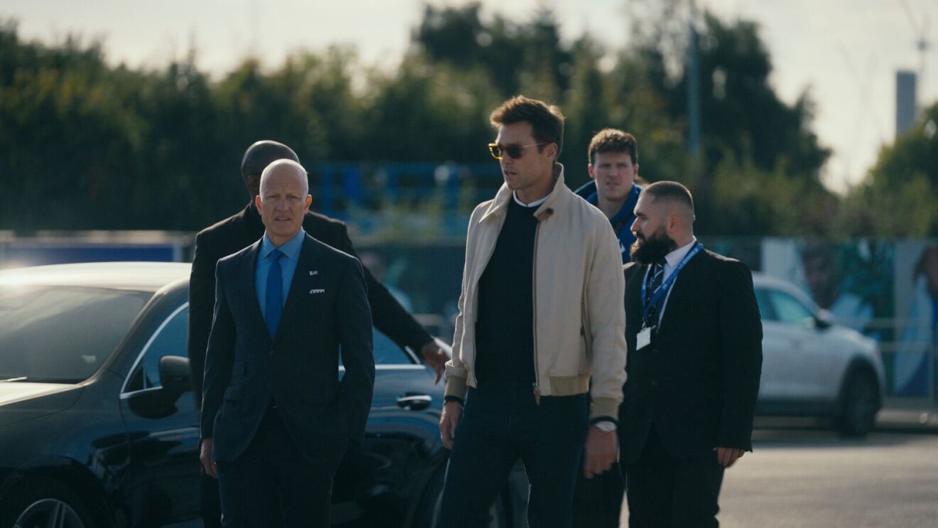 Tom Brady and a group of men stand in a parking lot