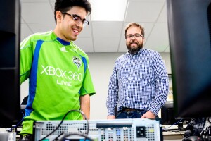 A teacher and a teacher observing a computer that is open and laid on a desk top.