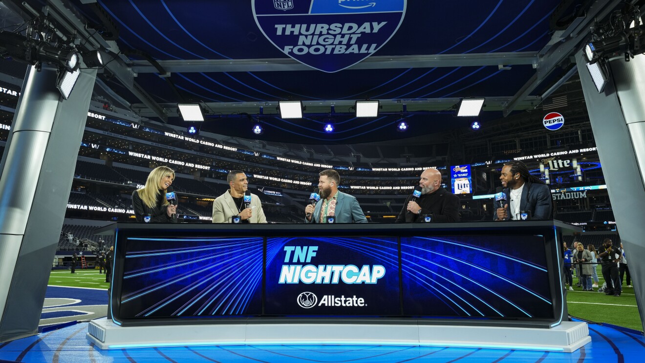 Five sports commentators talk at a blue desk following a Thursday Night Football game.