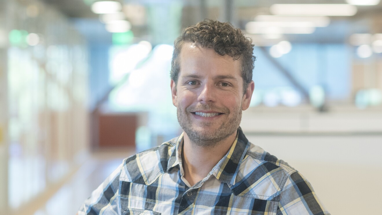 A man wearing a plaid shirt, smiling at the camera.