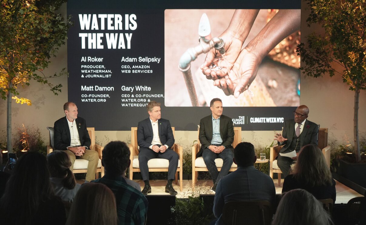 A photo of AWS CEO Adam Selipsky with Water.org co-founders Matt Damon and Gary White on stage in a panel format at Climate Week NYC 2022.