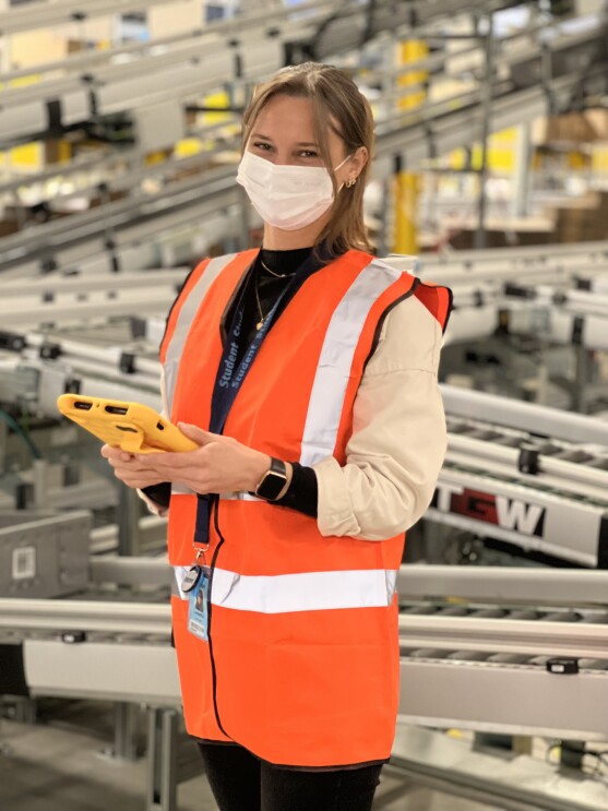 Azubi Leandra Stengel mit Maske und Tablet während ihrer Ausbildung bei Amazon