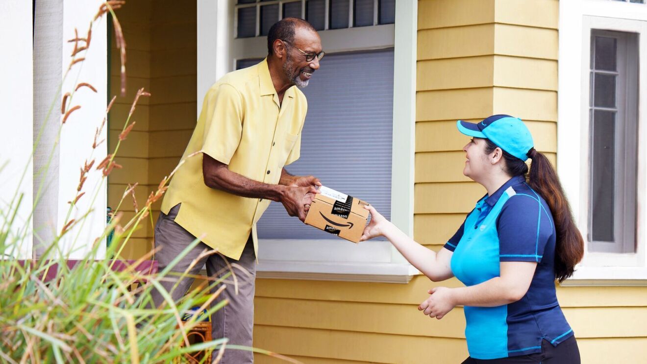 An image of an Amazon employee delivering a package to a man.