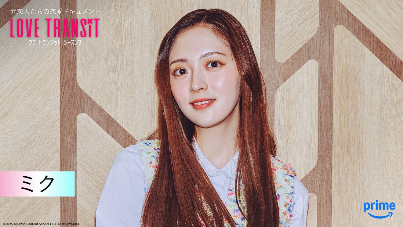 木目調の壁の前に立つ人物のバストアップ。左上隅に「LOVE TRANSIT」の文字。左下に「ミク」と名前が表示されている。