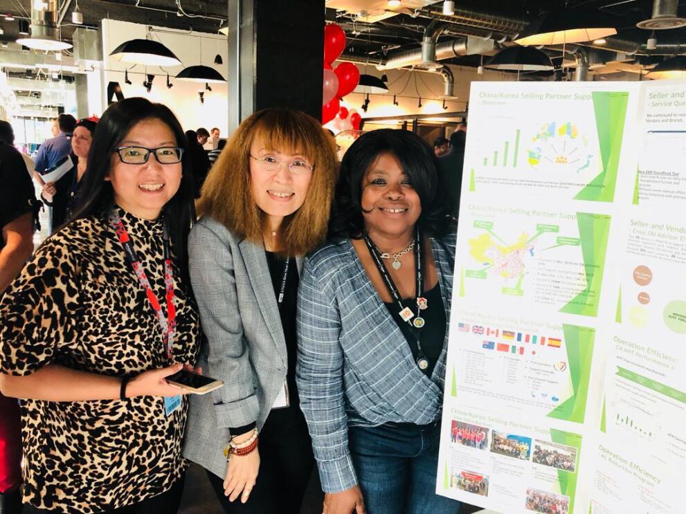 Nancy Dalton and two other women smile for a photo at a conference in front of a chart board with graphs on it. 