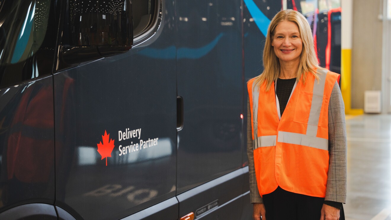 Image of a woman posing in front of an Amazon x Rivian delivery van