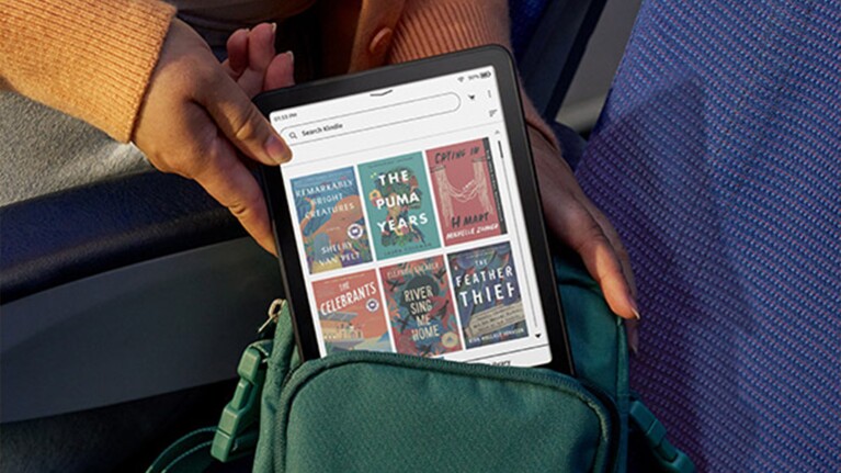 Hands holding a Kindle displaying book covers on Amazon Kindle store