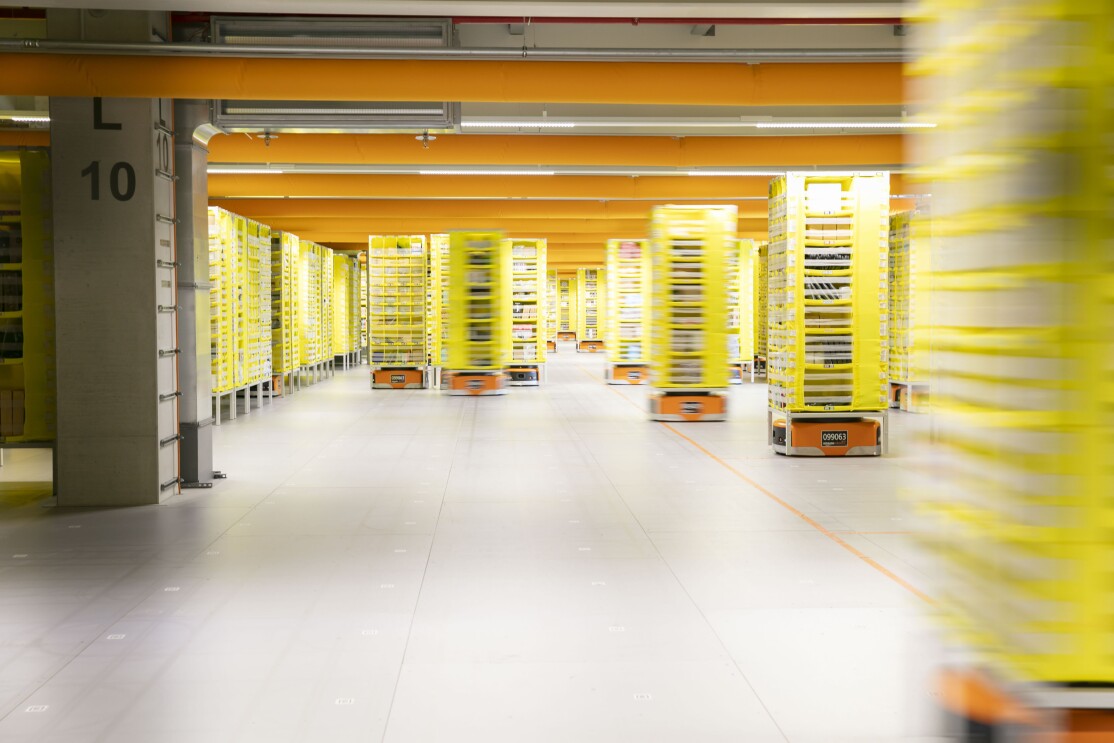 Schmale gelbe Regale werden von den Transportrobotern durch das Logistikzentrum transportiert.