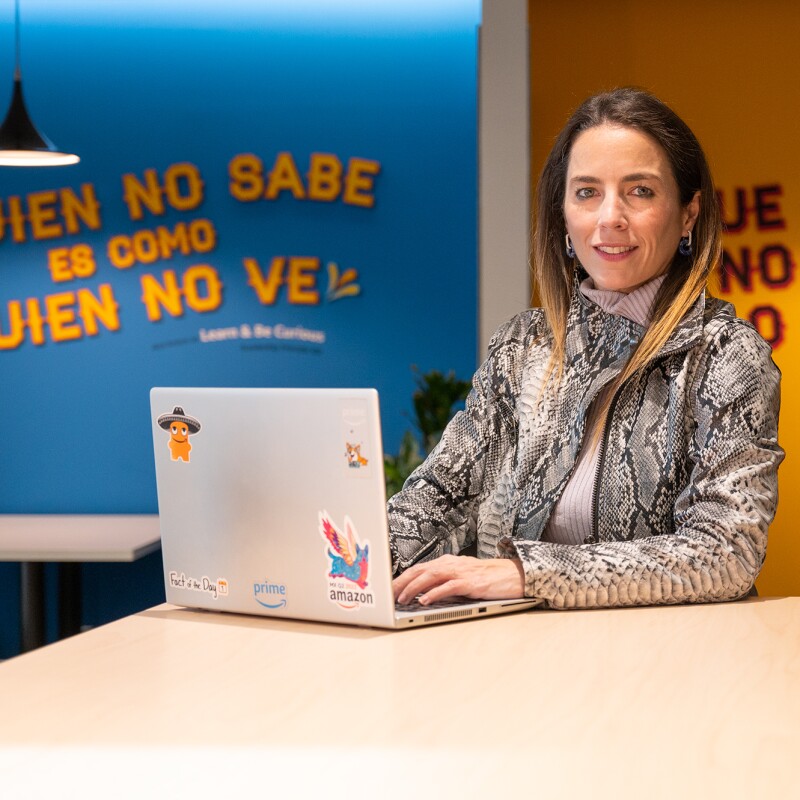 Una imagen de una empleada de Amazon trabajando en su laptop y sonriendo a la cámara.