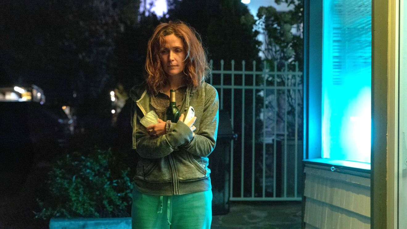 A disheveled woman holds a wine bottle