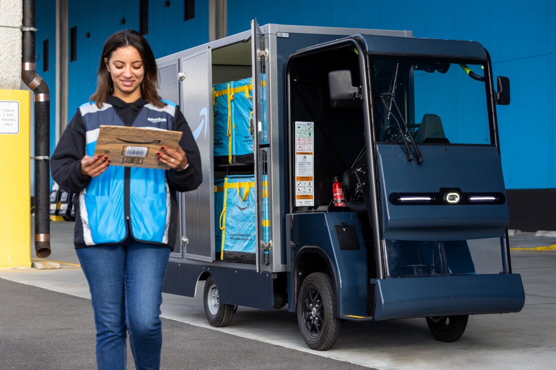 An Amazon delivery driver walks away from an e-cargo bike with a package.