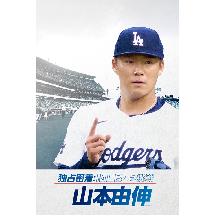 白地に青でDodgersと書かれた野球ユニフォームを着ている男性（山本由伸さん）が人差し指を上げている。その背景には野球場のスタンドが見える