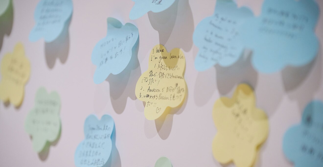 ホワイトボードにたくさんの花形付箋が貼られている。付箋には英語や日本語で文字が書かれている。