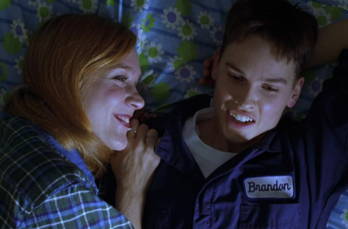Two women smiling and lying on a bed together