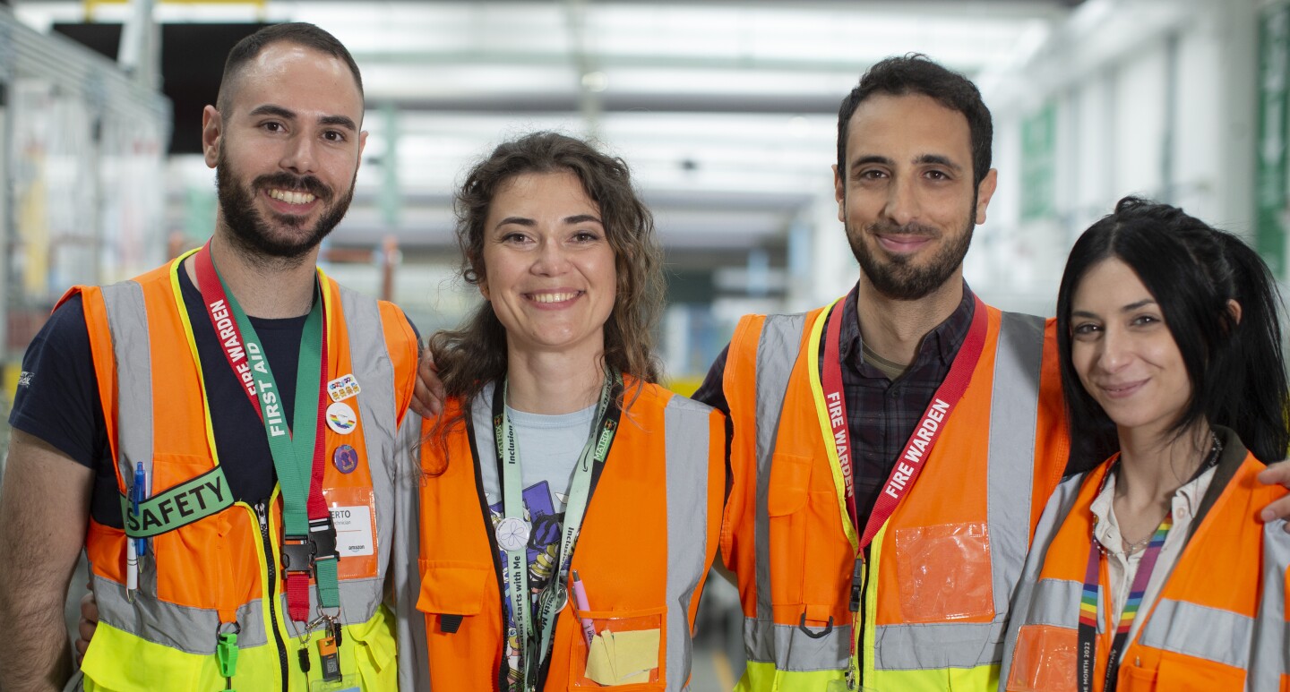 Team safety DLO1: four young men and women in orange vests are smiling at the camera