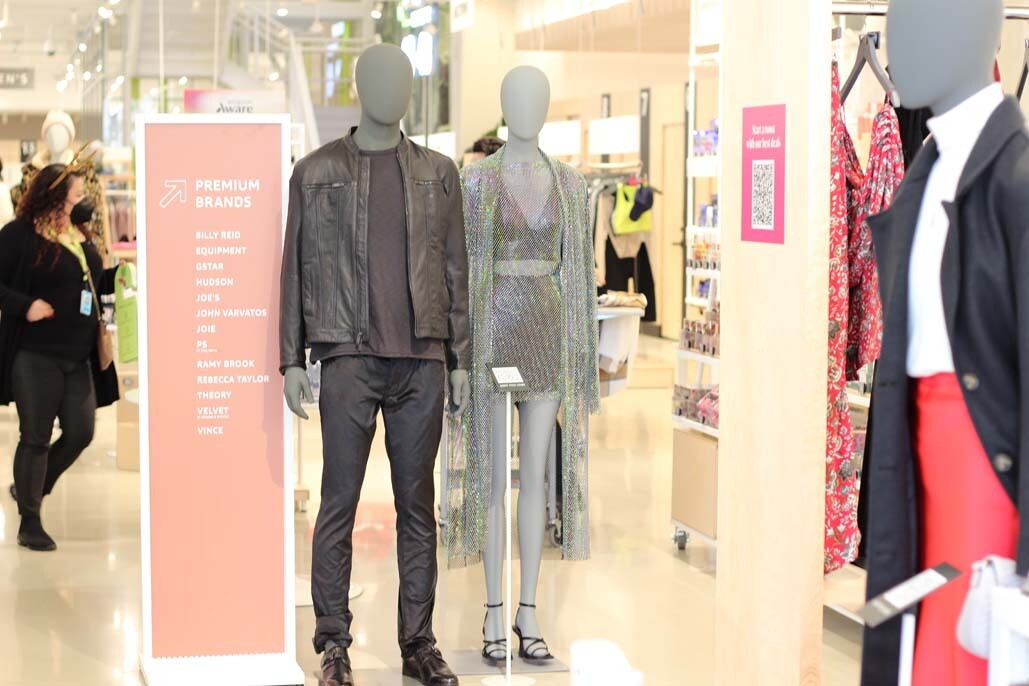 A display of clothing on two mannequins. One is a man wearing an all black outfit with a leather jacket and the other is a woman wearing a sparkly halter top and skirt set with a sparkly duster jacket.