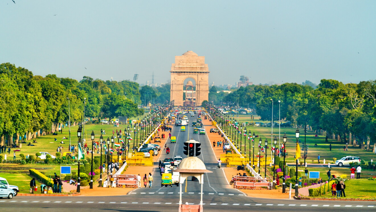 Wide boulevard lined with trees leading to India Gate monument in New Delhi